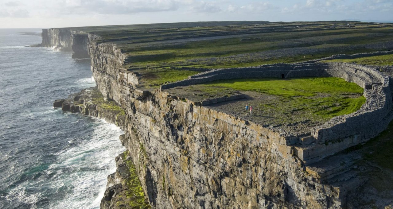 Visitors on Inishmore stand at the edge of the clifftop fort, Dún Aonghasa, and gaze out at the Atlantic ocean